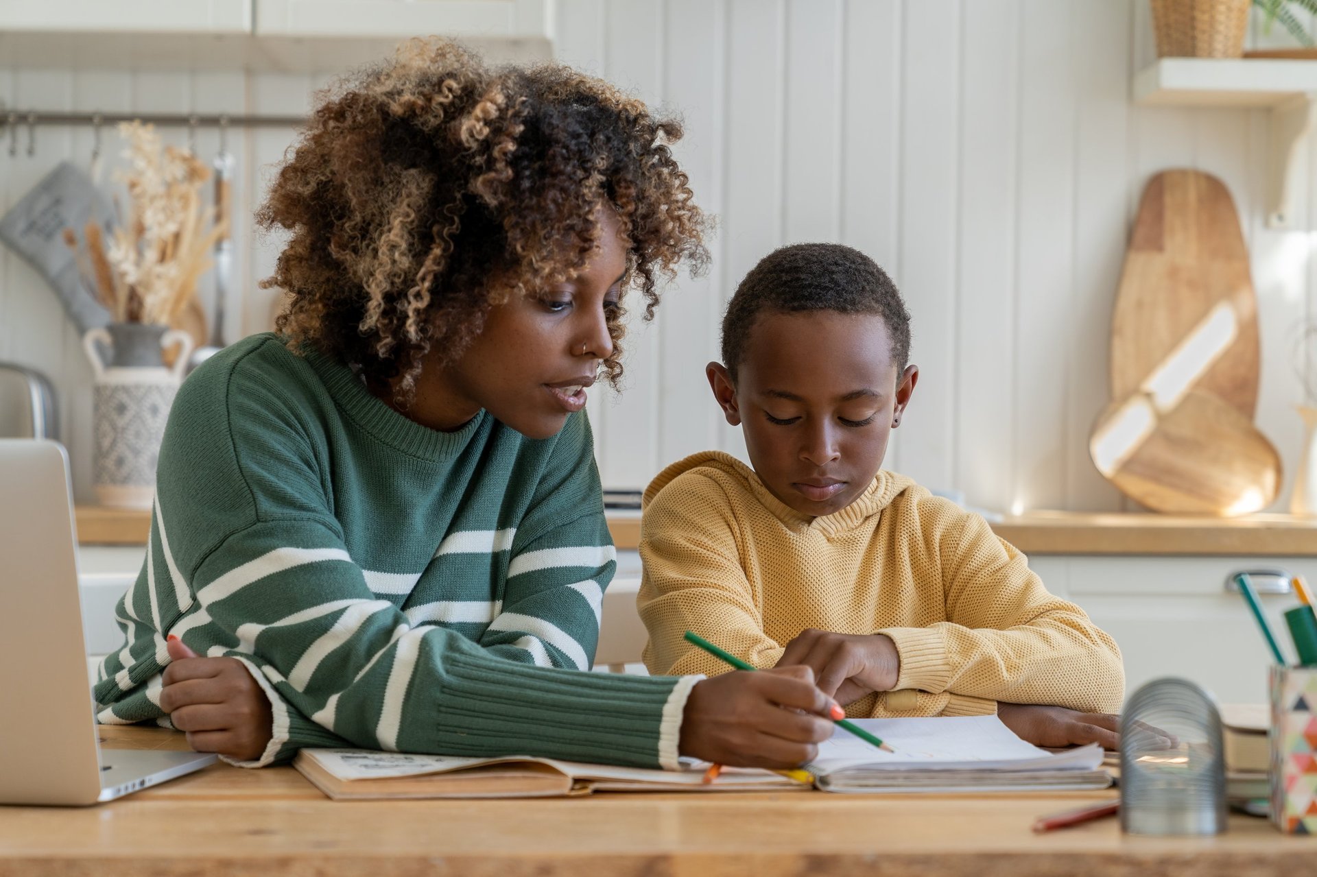 Focused biracial mother explaining difficult school task to attentive son for effective learning