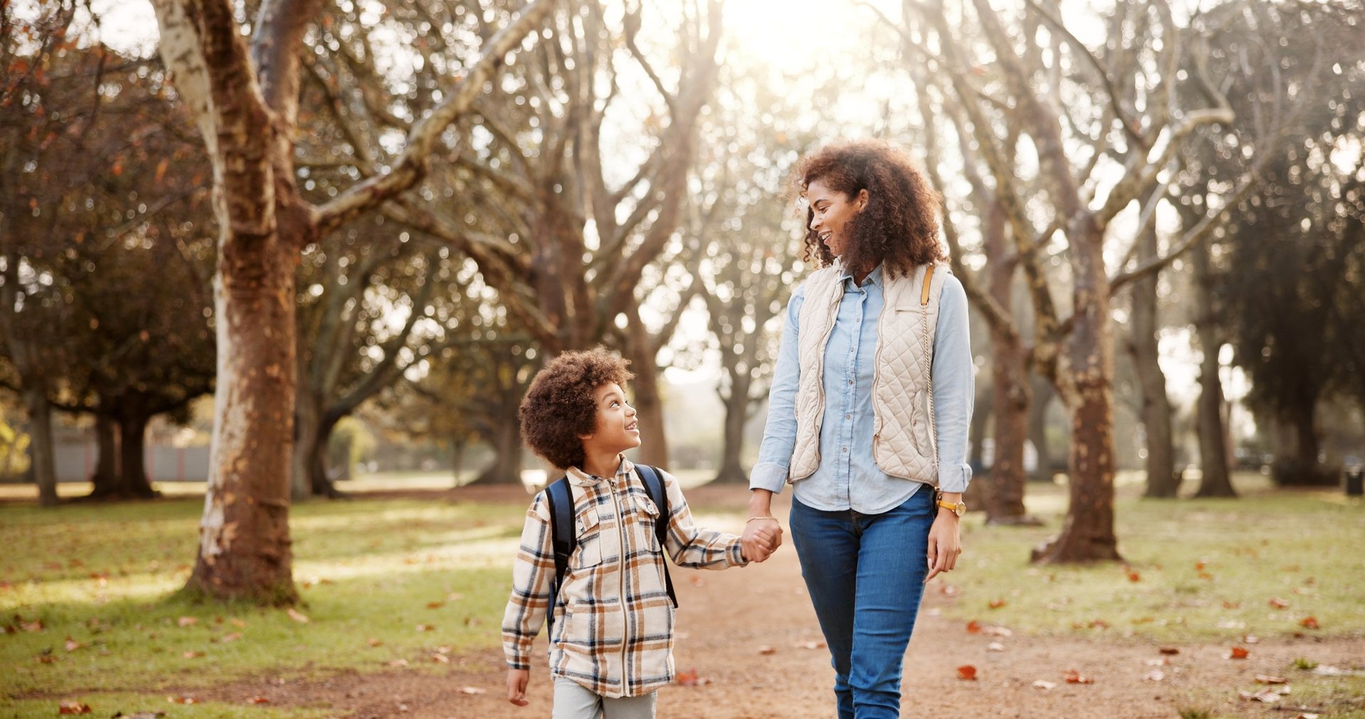 Mother and child holding hands while walking to school together