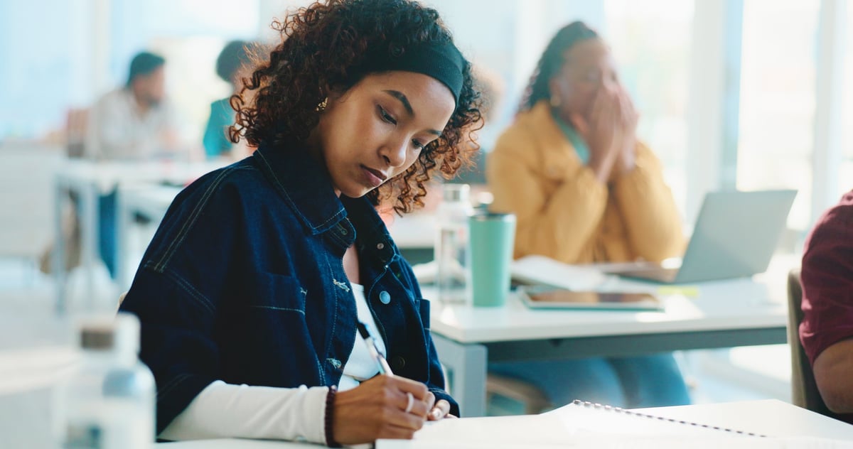 Woman, college student and writing with book in classroom for development, learning and scholarship. Person, notes and attention with project, assessment and education with solution at university